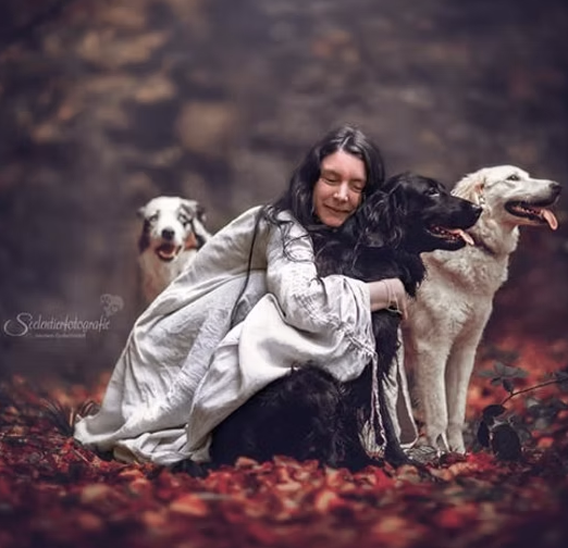 Manuela umarmt liebevoll ihre Hunde im herbstlichen Wald